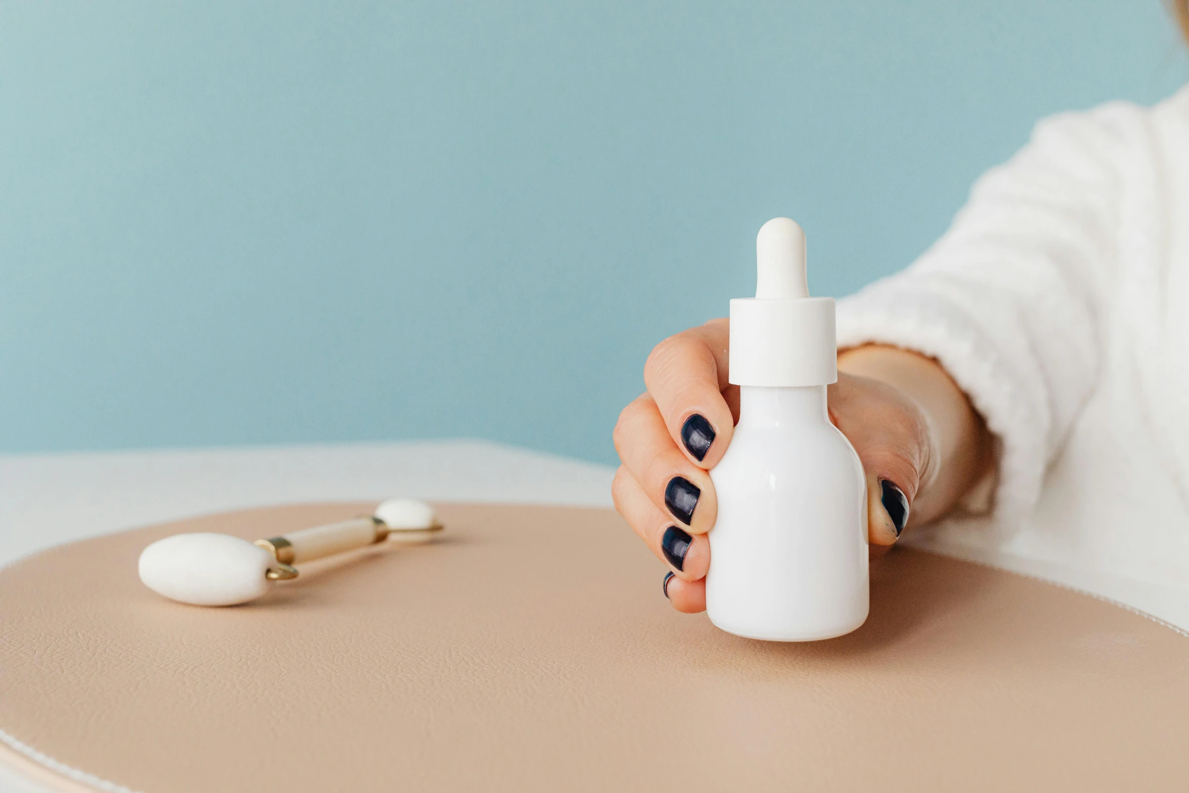 a woman sitting at a table with a bottle of liquid, trending on pexels, skin detail, soft white rubber, anaesthetic, flat lay