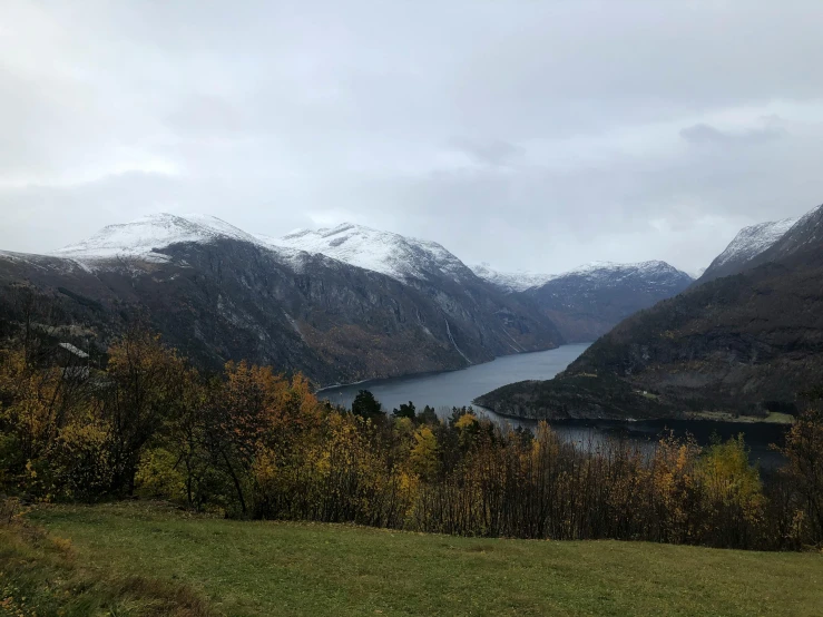 a large body of water sitting on top of a lush green hillside, by Tom Wänerstrand, pexels contest winner, hurufiyya, snowy fjord, autum, seen from outside, phone photo