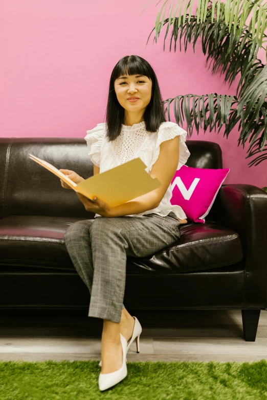 a woman sitting on a couch reading a book, inspired by Yuko Tatsushima, sat in an office, pink accents, vp of marketing, v tuber