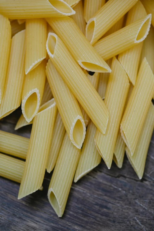 a pile of pasta sitting on top of a wooden table, straight smooth vertical, pikes, vanilla, a pair of ribbed