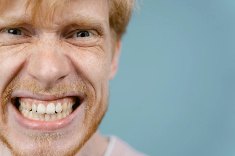 a close up of a person with a tooth brush in his mouth, by Tobias Stimmer, trending on pexels, hyperrealism, ginger hair, goofy smile, small blond goatee, bearing a large mad grin