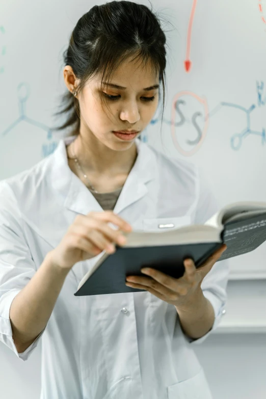 a woman in a lab coat reading a book, pexels contest winner, academic art, synthetic materials, formulas, girl wearing uniform, profile image