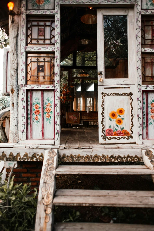 a small house sitting on top of a lush green field, by Julia Pishtar, trending on unsplash, arts and crafts movement, massive decorated doors, made of colorful dried flowers, ukraine. photography, wooden interior