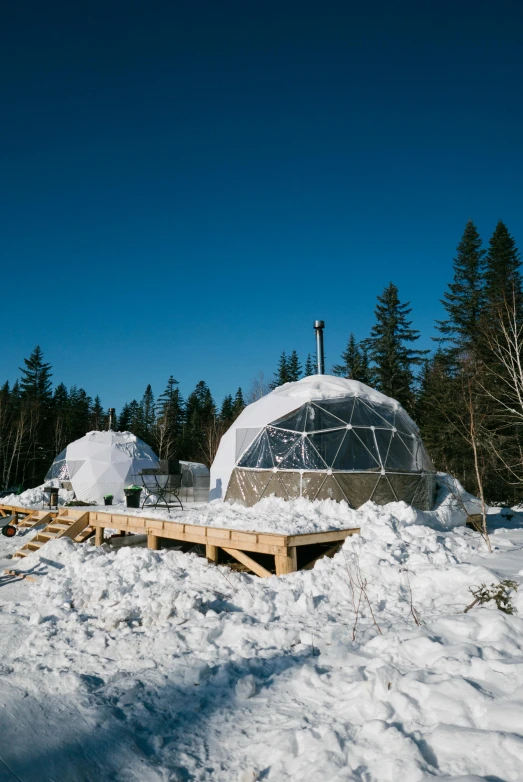 a group of people standing on top of a snow covered field, by Buckminster Fuller, temporary art, nestled in a forest, quebec, domes, mining outpost