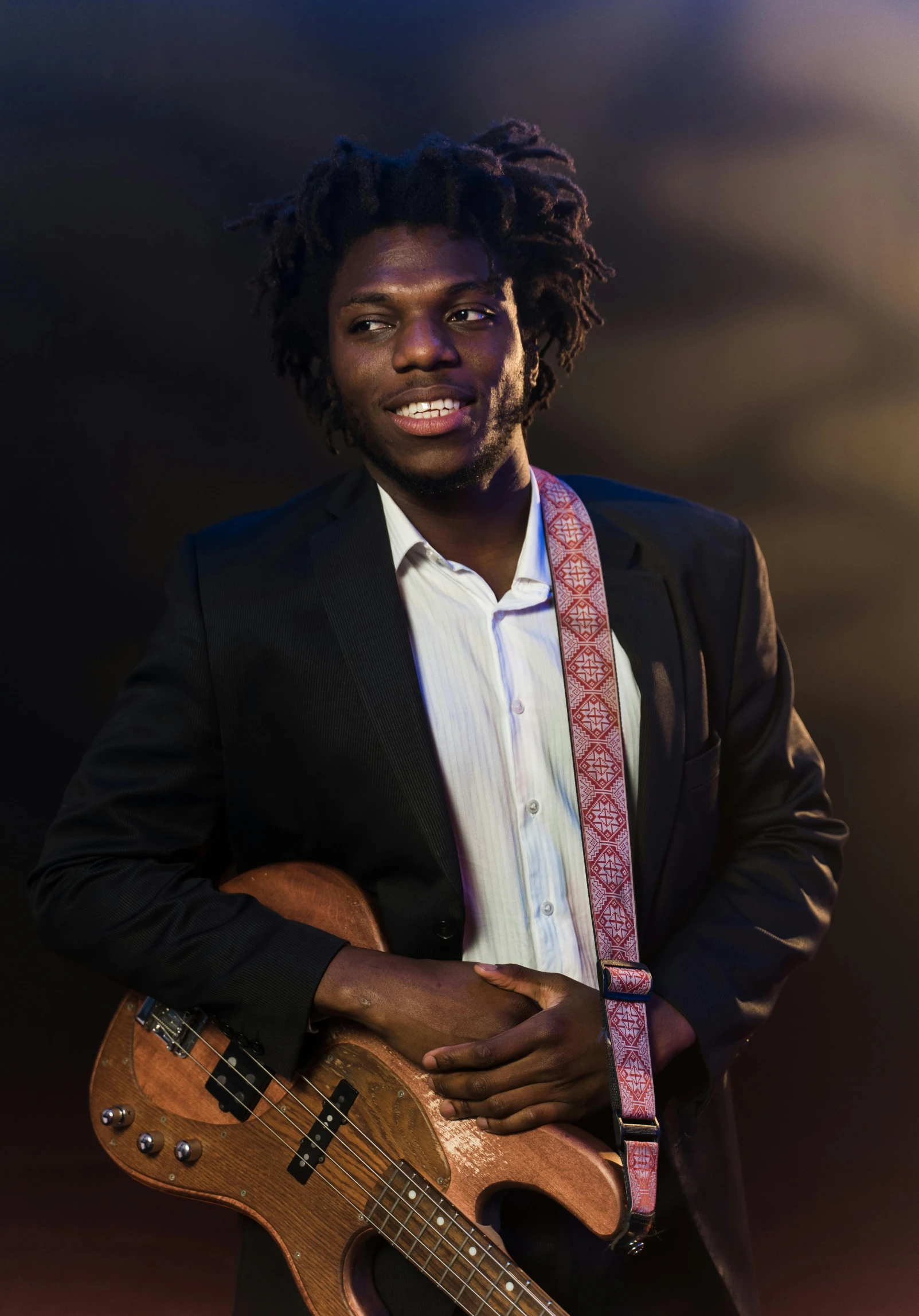 a man in a suit holding a guitar, by Stokely Webster, black man with afro hair, looking towards camera, liam brazier, ( ( dark skin ) )