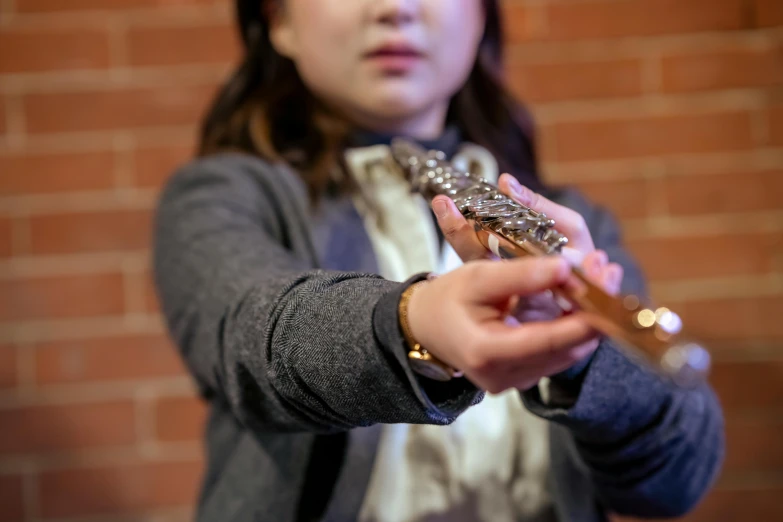 a woman holding a flute in front of a brick wall, unsplash, ukulele, school class, holding a silver electric guitar, multiple stories