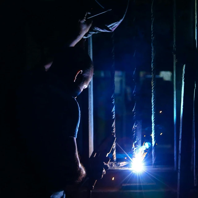 a welder working on a piece of metal, a portrait, by Andrew Allan, pexels contest winner, blue backlight, instagram post, medium format. soft light, late night