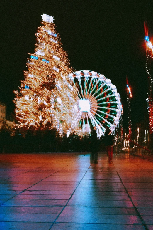 a ferris wheel in front of a christmas tree, a picture, pexels contest winner, happening, square, blurry footage, fuji superia, town square