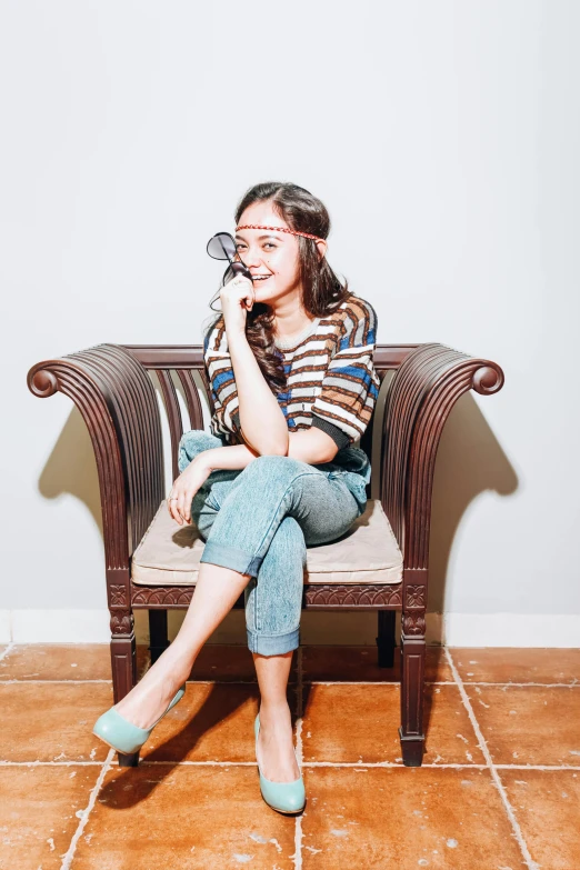 a woman sitting on a chair talking on a cell phone, inspired by Kim Jeong-hui, pexels contest winner, aestheticism, wearing jeans, striped, cute slightly nerdy smile, portrait of modern darna