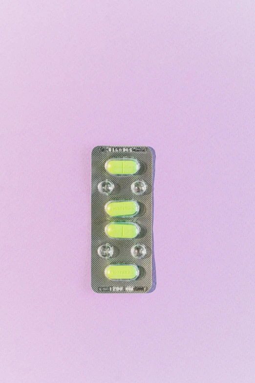 a pill pack sitting on top of a pink surface, by Jan Rustem, pexels, pop art, pale green glow, yellow purple green black, back facing, leds