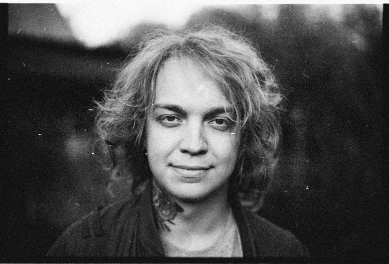 a black and white photo of a man with long hair, a black and white photo, inspired by Lasar Segall, frank dillane as puck, 35mm color lomography, her hair is natural disheveled, very slightly smiling