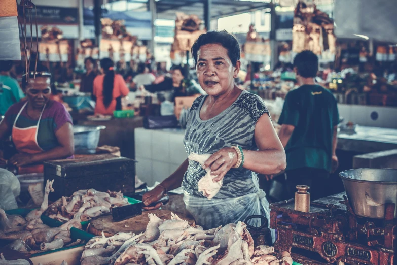 a woman standing in front of a table full of food, by Sam Dillemans, pexels contest winner, fish market stalls, avatar image, batik, square