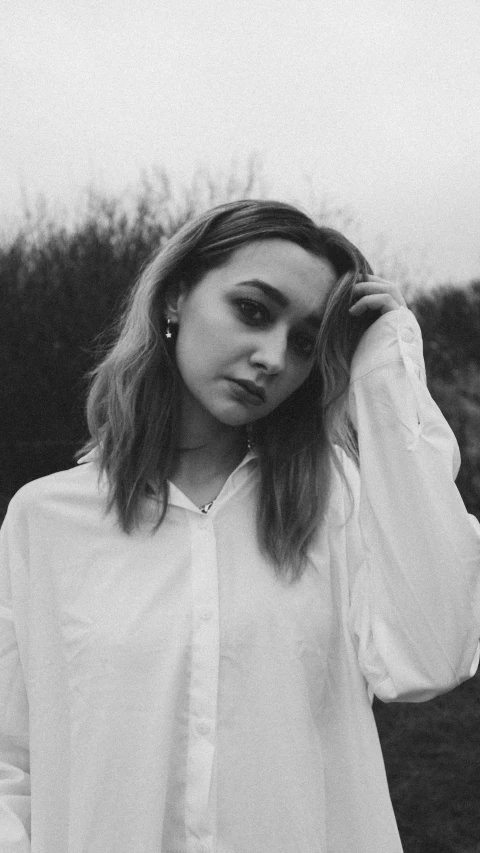 a black and white photo of a woman in a field, a black and white photo, inspired by Maud Naftel, unsplash, realism, wearing a white button up shirt, portrait sophie mudd, portrait of kim petras, portrait!!!