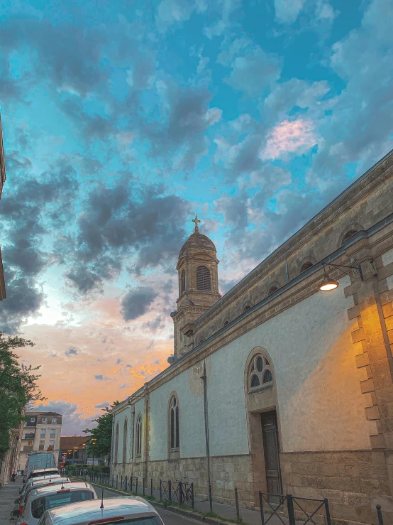 a street with cars parked on the side of it, an album cover, by Matteo Pérez, pexels contest winner, post-impressionism, panorama view of the sky, church, summer evening, tlaquepaque