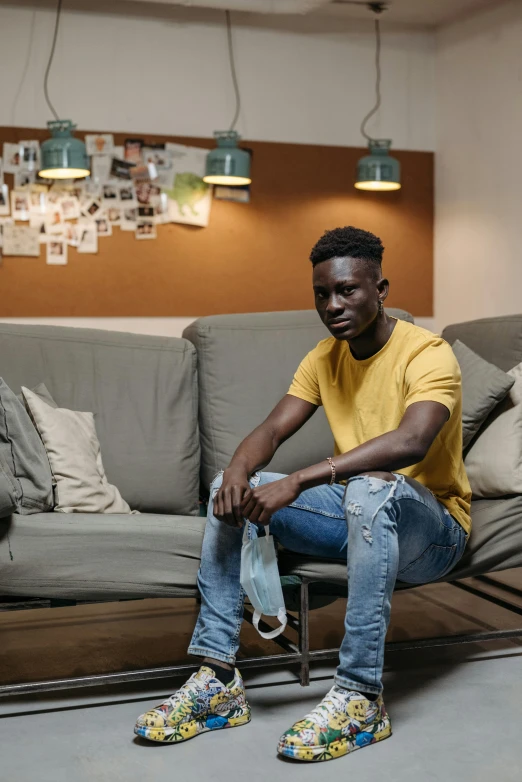 a man sitting on a couch in a living room, pexels contest winner, adut akech, young greek man, jaylen brown, covid-19 as a human