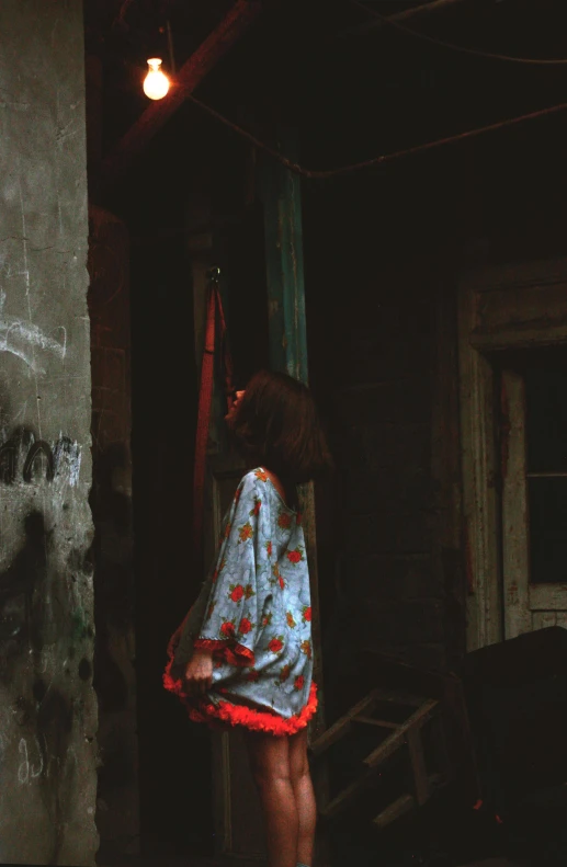 a woman standing next to a wall with graffiti on it, an album cover, inspired by Elsa Bleda, pexels contest winner, red kimono, inside a haunted house, color film photography 1970s, young girl