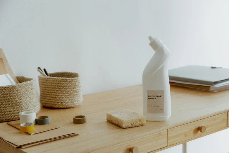 a bottle of cleaner sitting on top of a wooden desk, pexels contest winner, minimalism, white ceramic shapes, ingredients on the table, high resolution product photo, sweeping