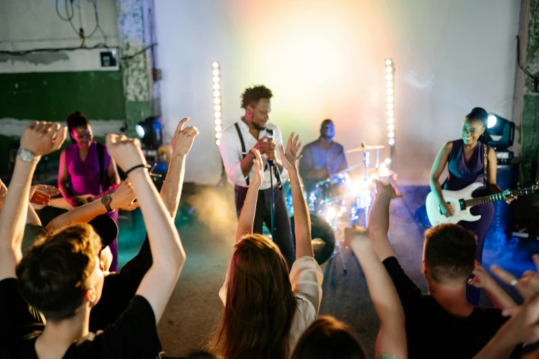 a group of people with their hands in the air, an album cover, pexels contest winner, happening, small people with torches, wedding, singing into microphone, light room