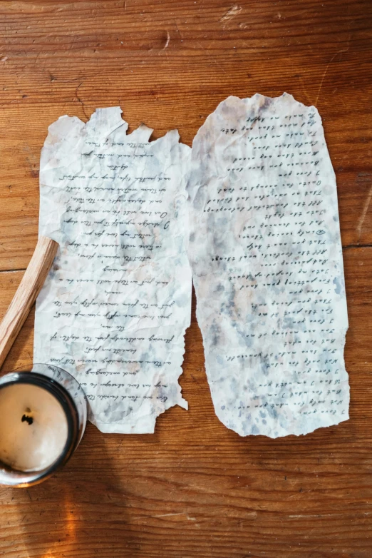 a cup of coffee sitting on top of a wooden table, on vellum, weathered artifacts, with some hand written letters, 1 6 x 1 6