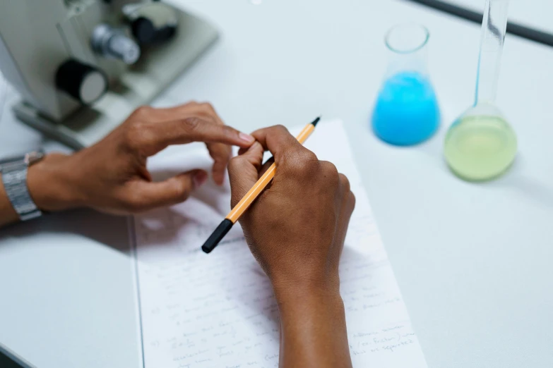 a person writing on a piece of paper with a pencil, in a lab, essence, uploaded, multiple stories