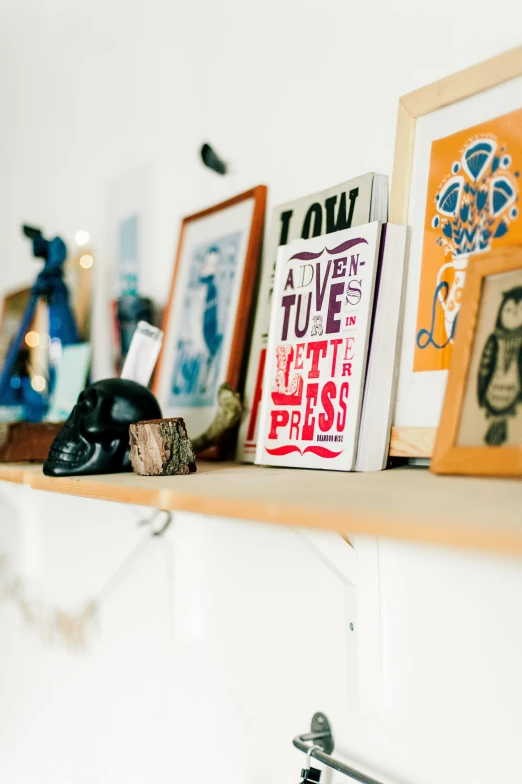 a shelf that has some pictures on it, a screenprint, by Jessie Algie, unsplash, private press, quirky shops, brightly lit room, 9 9 designs, in a studio