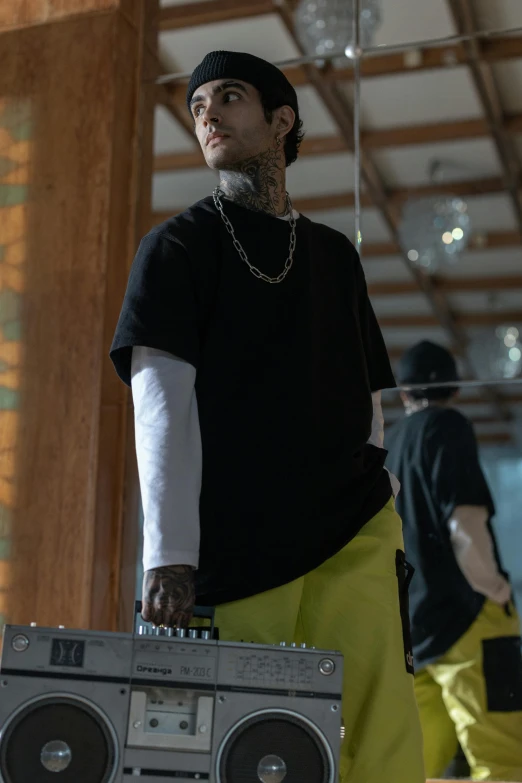a man standing next to a boombox in a room, inspired by Zhu Da, trending on pexels, hyperrealism, wearing yellow croptop, lil peep, action sports, standing on top of a piano