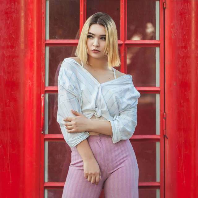 a woman standing in front of a red phone booth, a polaroid photo, inspired by Elsa Bleda, pexels contest winner, realism, dove cameron in a knight armor, loose - fitting blouses, maisie williams, attractive young woman