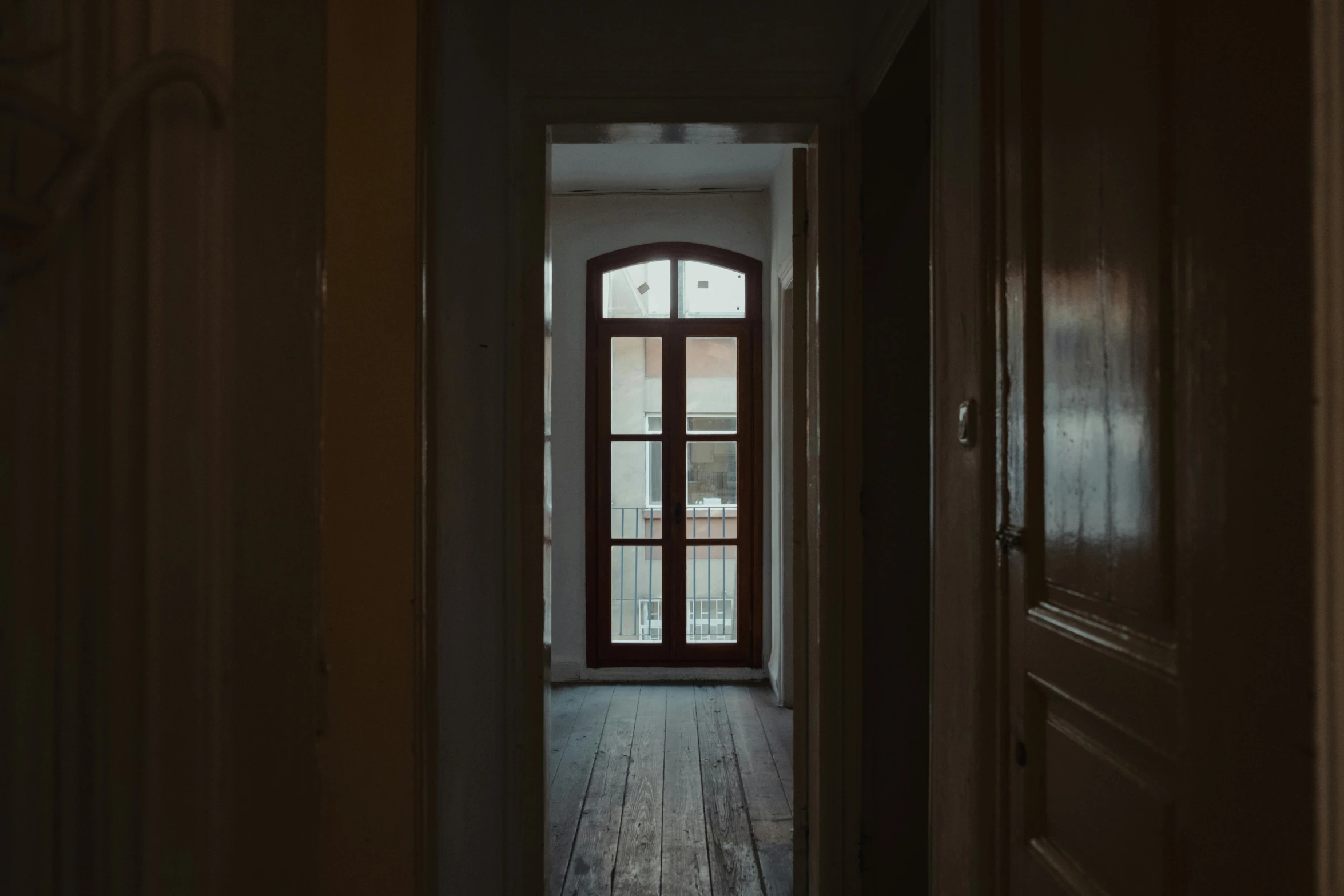 a dark hallway leading to an open door, a picture, inspired by Elsa Bleda, pexels contest winner, old apartment, wide windows, wood door, in a white room