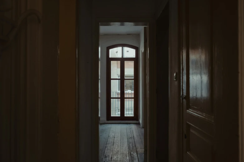 a dark hallway leading to an open door, a picture, inspired by Elsa Bleda, pexels contest winner, old apartment, wide windows, wood door, in a white room