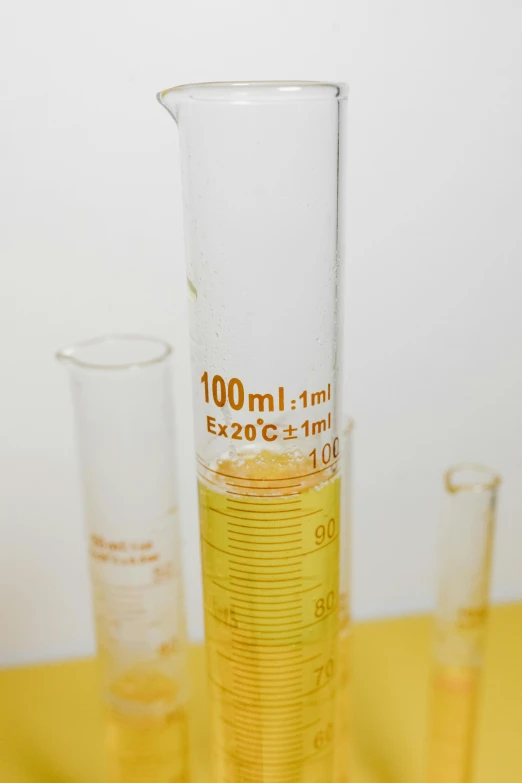 a glass filled with liquid sitting on top of a yellow table, pathology sample test tubes, really long, product image, alchemist bottles