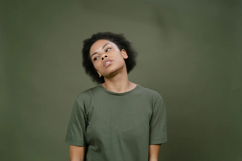 a woman standing in front of a green wall, pexels contest winner, hurufiyya, in a dark green polo shirt, mixed-race woman, olive, ( ( dark skin ) )