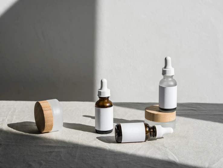 a couple of bottles sitting on top of a table, by Emma Andijewska, trending on pexels, minimalism, medical labels, a wooden, white, miniature product photo