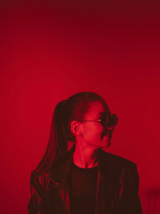 a woman standing in front of a red light, pexels contest winner, antipodeans, portrait of ariana grande, dark shades, red room, profile image