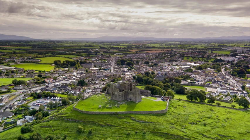 a large castle sitting on top of a lush green field, by Eamon Everall, drone view of a city, arney freyag, high-res, 2000s photo