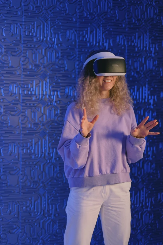 a woman standing in front of a blue wall wearing a virtual reality headset, a blond, paul barson, gesture dynamic, ariel perez