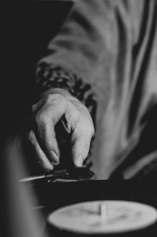 a black and white photo of a person playing a record, by Adam Marczyński, hand holding a knife, conductor, closeup of hand, concentrated