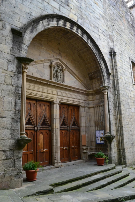 a couple of wooden doors sitting on top of a stone building, by Carlo Carrà, romanesque, tall entry, cathedrals