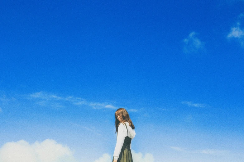 a woman standing on top of a lush green field, a picture, by Jang Seung-eop, unsplash, magical realism, cloudless blue sky, lofi album art, uniform off - white sky, girl with brown hair