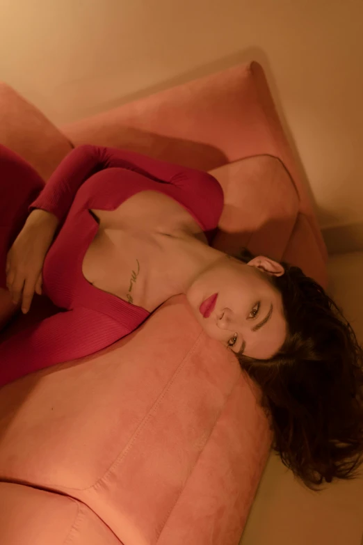 a woman laying on top of a pink couch, an album cover, inspired by Elsa Bleda, trending on pexels, renaissance, red body suit, pouting, high angle shot, profile pic