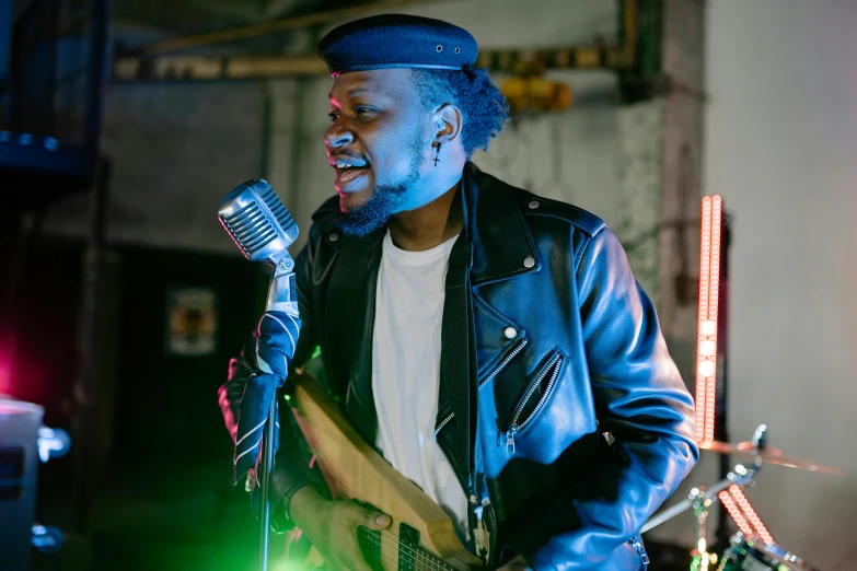 a man in a leather jacket singing into a microphone, unsplash, felix the cat, riyahd cassiem, holding a silver electric guitar, bright lights