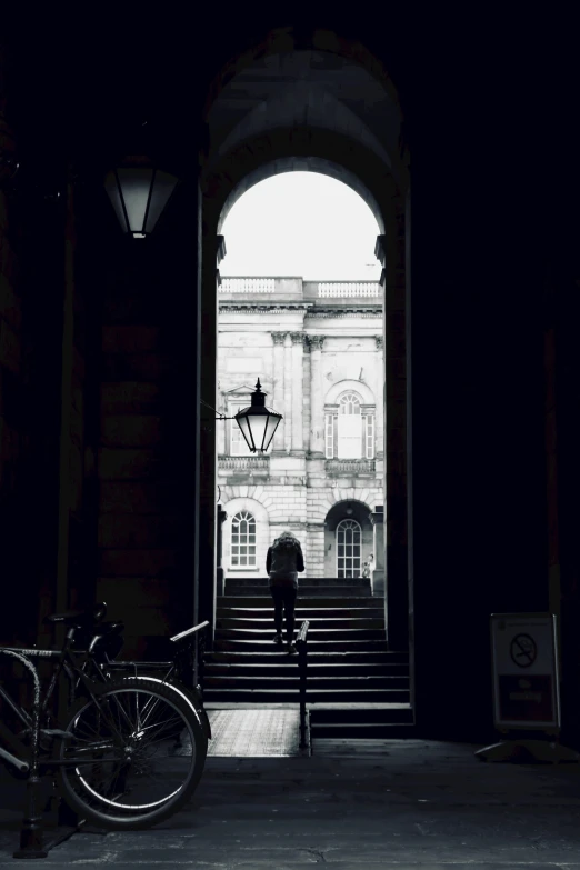 a black and white photo of a bike in front of a building, inspired by Henry Macbeth-Raeburn, pexels contest winner, academic art, girl under lantern, arched doorway, view from the back, inside a museum