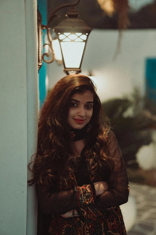 a woman leaning against a wall with her arms crossed, by Riza Abbasi, during night, young with long hair, happily smiling at the camera, multiple stories