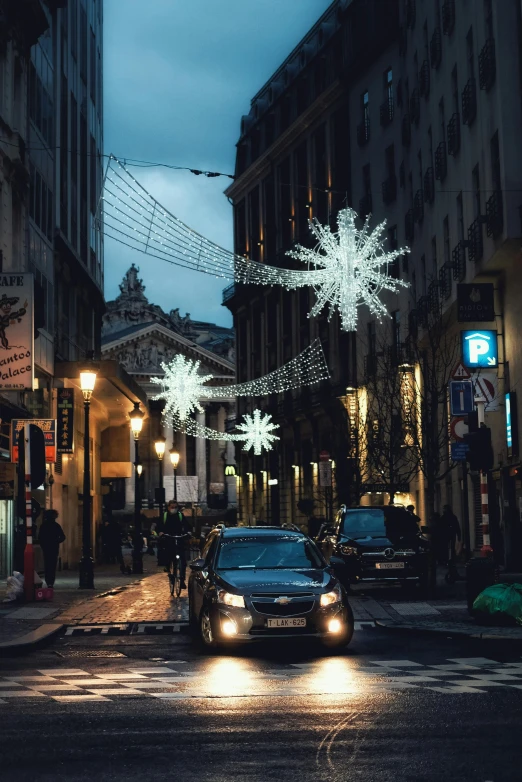 a car driving down a street next to tall buildings, a photo, pexels contest winner, renaissance, emitting light ornaments, crystal lights, gif, prefecture streets