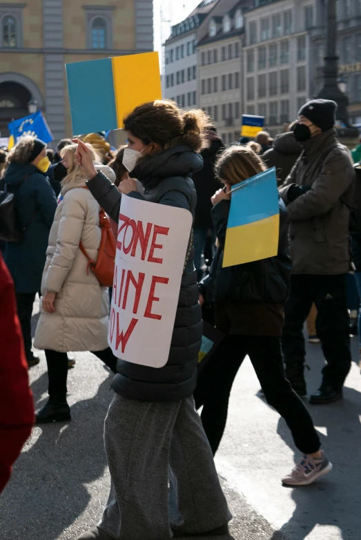 a group of people walking down a street holding signs, by Adam Marczyński, shutterstock, antipodeans, some yellow and blue, ukrainian, woman holding another woman, photograph taken in 2 0 2 0