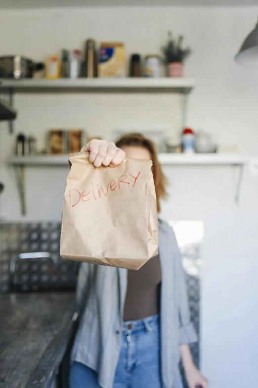 a woman holding a brown paper bag over her face, by Jessie Algie, pexels, renaissance, logo for lunch delivery, in a kitchen, a labeled, danny fox