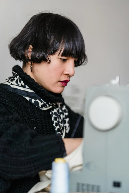 a woman is working on a sewing machine, by Nina Hamnett, black hair and white bangs, louise zhang, profile image, casually dressed