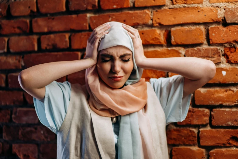 a woman standing in front of a brick wall, trending on pexels, hurufiyya, wearing a head scarf, stressing out, swollen muscles, woman holding another woman