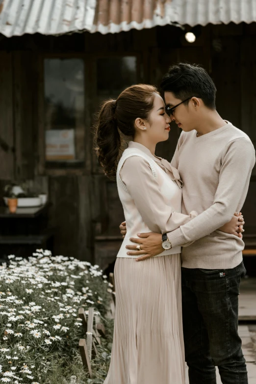 a couple standing next to each other in front of a building, a colorized photo, inspired by Ruth Jên, pexels contest winner, romanticism, on wooden table, asian, tenderness, square