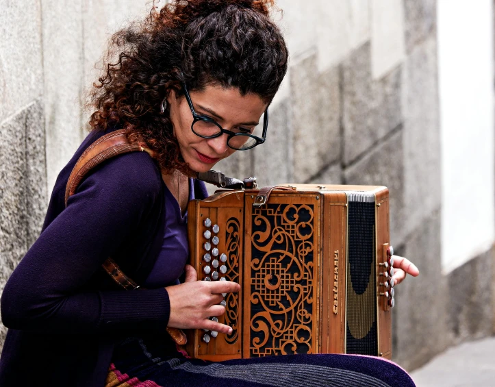 a woman sitting on the ground playing an accordion, an album cover, by Meredith Dillman, pexels contest winner, baroque, intricate carved wood, city views, greek ameera al taweel, square