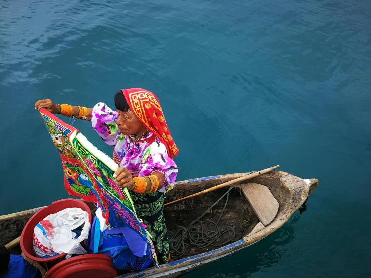 a person in a boat on a body of water, an album cover, by Gwen Barnard, pexels contest winner, sumatraism, colorful bandana, market, textiles, awarded winning photo